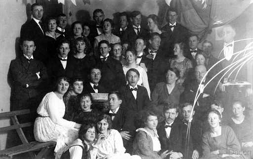 1919 Lysningskalas på Folketshus i Råneå.jpg - Lysningskalas på godtemplarhuset 1919 för fotografen Hildur Norberg Råneå och frisören Knut Sjöberg Luleå som efter arbetets slut skulle färdas med hästtaxi till Råneå det blev snöstorm och längre än till Sundom orkade inte hästarna så knut kom en dag för sent till kalaset. - Det ser ut som om knut har en reserverad plats på bänken intill Hildur. – det bjöds på kaffe med bröd, äpplen och dans - den som svarade för tonerna var speleman sven Johansson med sitt dragspel, inte många ansikten jag känner igen men till v. står Hjalmar Berg med händerna i kors ovanför syns två herrar Bergman med fruar i mitten mot vit klänning syns Ivan Larsson nere i vitt sitter Hildurs syster Agnes Norberg och mellan syskonen syns Anna Johansson